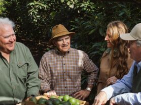 California Avocado growers John Lamb, David Lamb, Maureen Lamb Cottingham, and Robert Lamb gathered around a box of avocados smiling