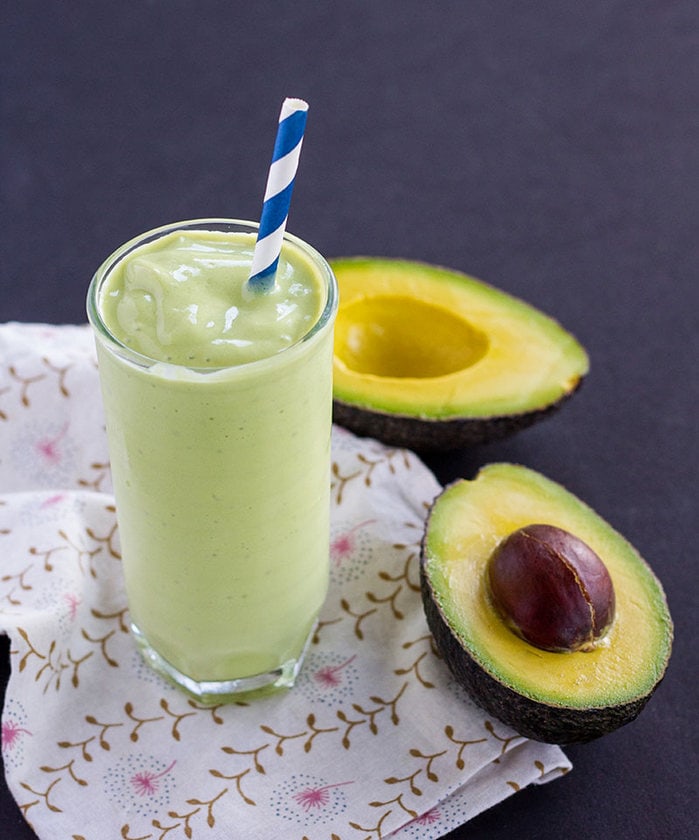 Avocado-Milkshake-3.jpg Avocado milkshake next to a halved avocado.