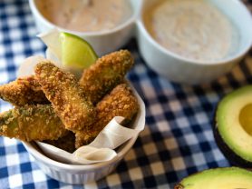 Fried avocado dippers next to bowls of sauce