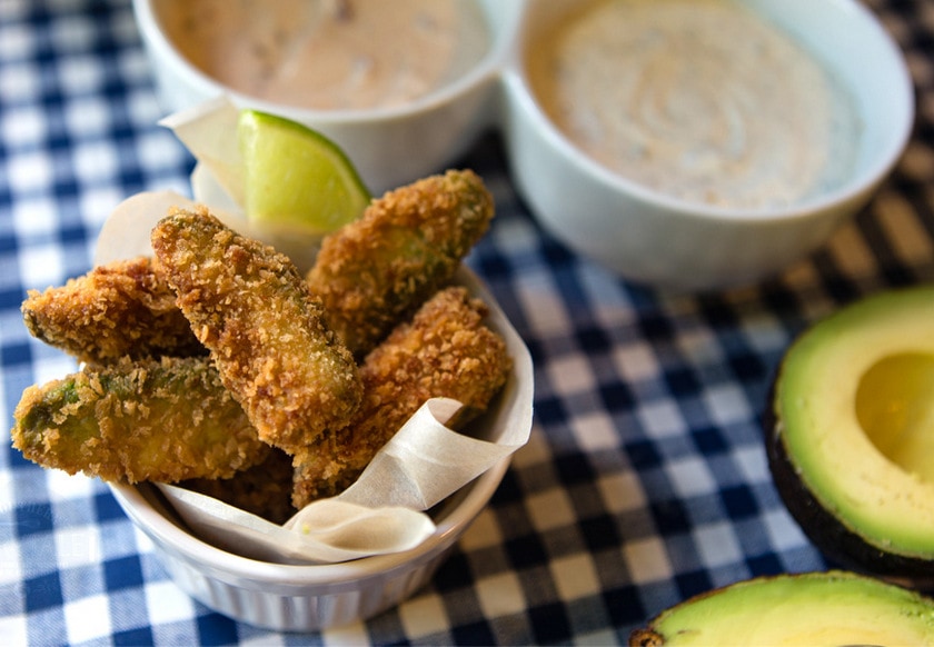 Fried avocado dippers next to bowls of sauce