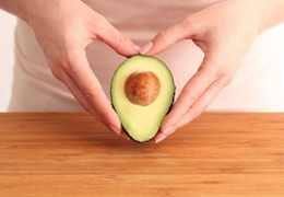 Two hands holding half an avocado