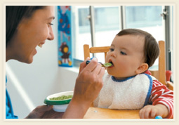 Baby being fed mashed avocado